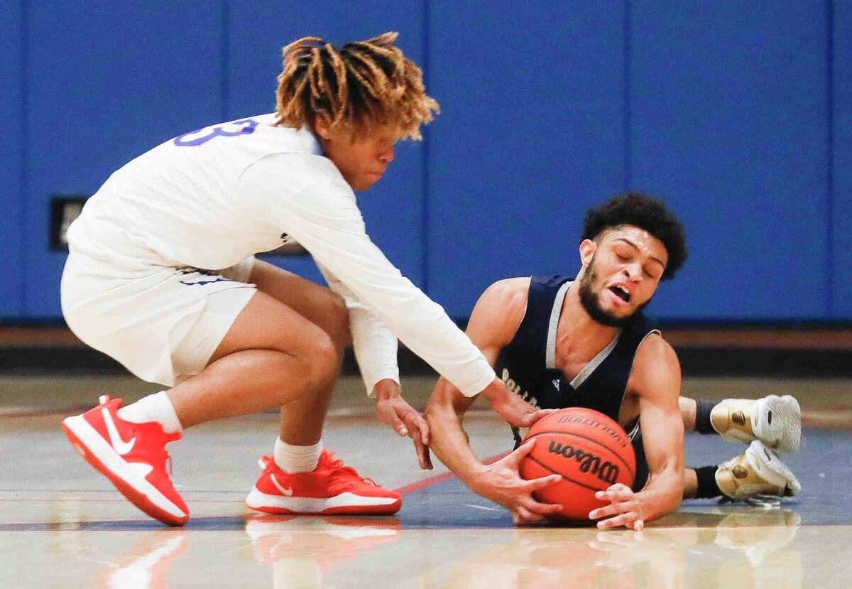 College Park guard Nate Murphy (0) dives on a loose ball against Grand Oaks point guard Jordan Reece (3) during the second quarter of a high school basketball game at Grand Oaks High School, Tuesday, Jan. 11, 2022, in Spring.