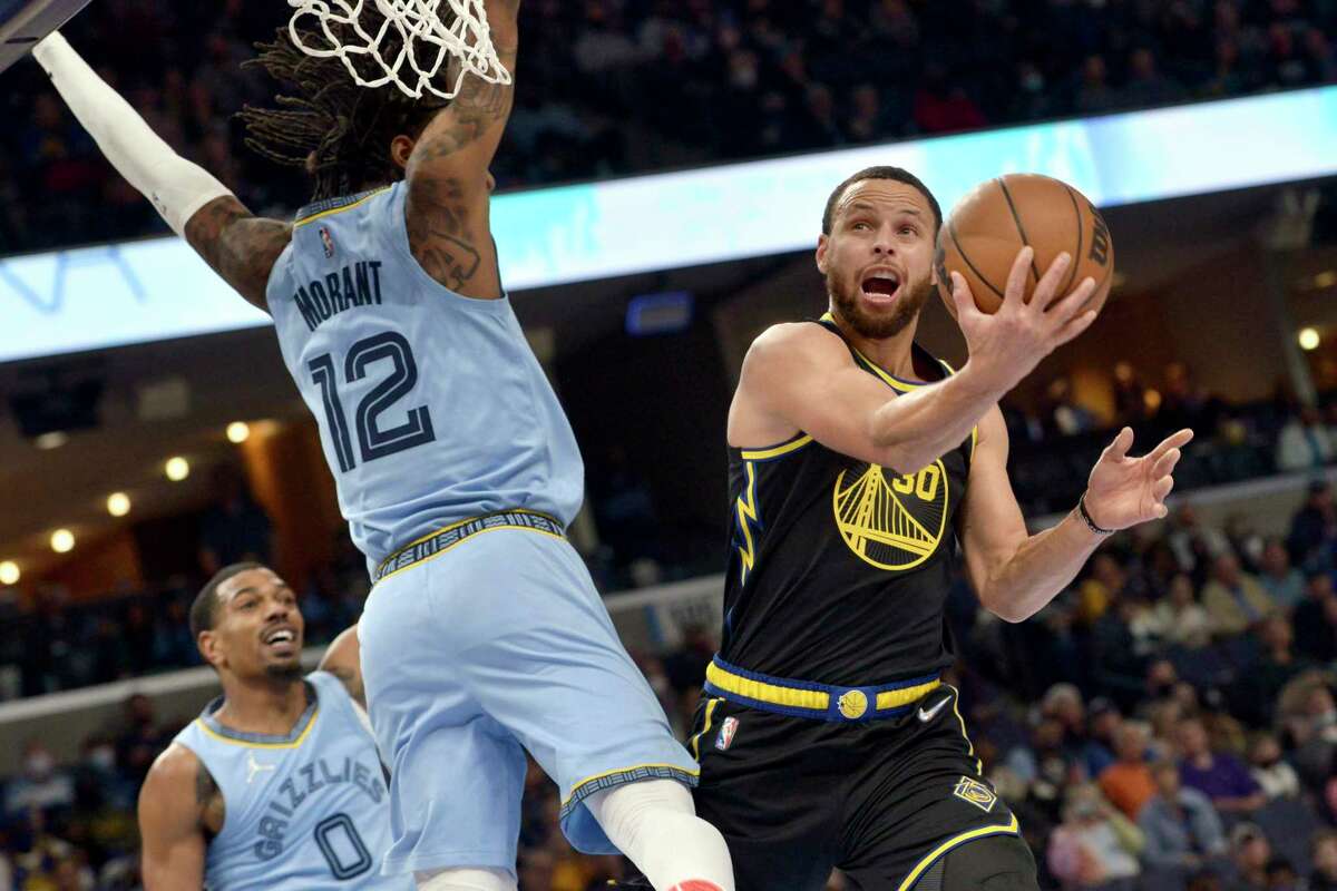 Golden State Warriors guard Stephen Curry (30) shoots as Memphis Grizzlies guard Ja Morant (12) defends in the first half of an NBA basketball game Tuesday, Jan. 11, 2022, in Memphis, Tenn. (AP Photo/Brandon Dill)