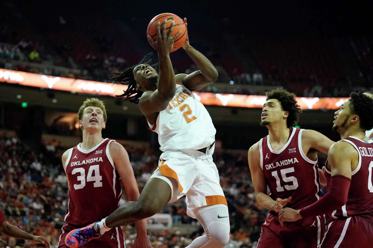 Texas guard Marcus Carr drives to the hoop between Oklahoma forwards Jacob Groves (34) and Ethan Chargois.