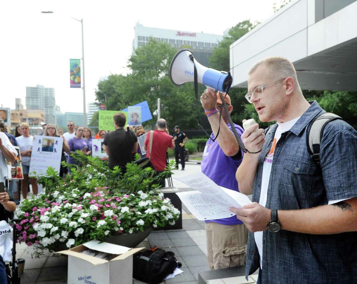 Ryan Hampton, at right, speaks during a protest on Aug. 17, 2018 outside the headquarters of OxyContin Purdue Pharma, at 201 Tresser Blvd., in downtown Stamford, Conn. In a series of tweets on Monday, Jan. 10, 2022, Hampton criticized Connecticut Attorney General William Tong for his opposition to Purdue’s settlement plan.