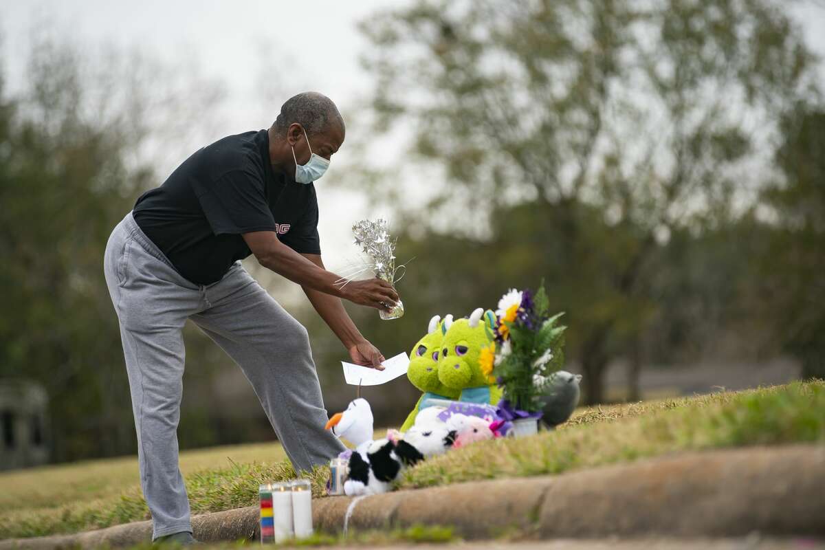 A man puts down a note at a makeshift memorial near the site along Park Manor Drive and Markwood Lane where a 15-year-old girl was shot and killed over night, Wednesday, Jan. 12, 2022, in Houston.