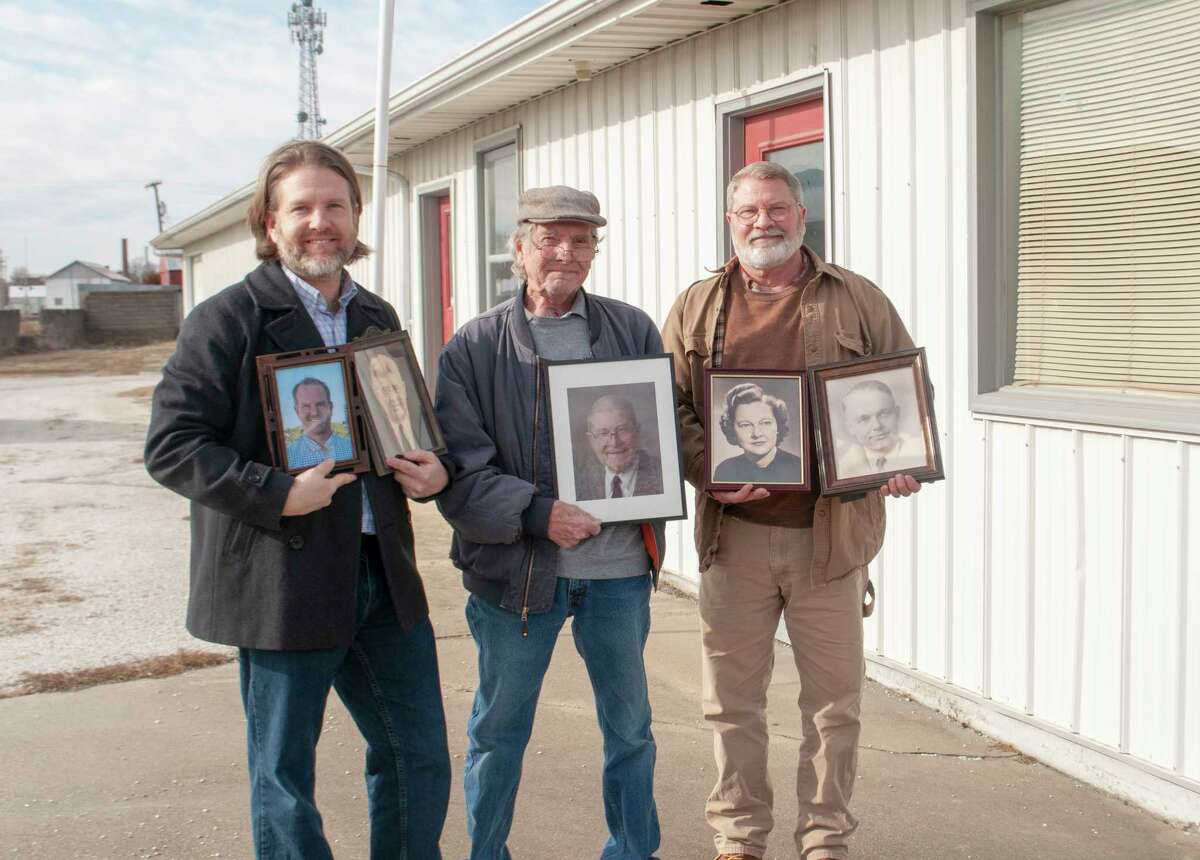 Bryan Leonard (from left) stands with his father, Jeff Leonard, and uncle Jay Leonard in front of the building at 509 N. East St., where their family business, Leonard & Six Plumbing, was open for 94 years. The three are holding pictures of family members who either owned or worked at the company during the past 94 years.