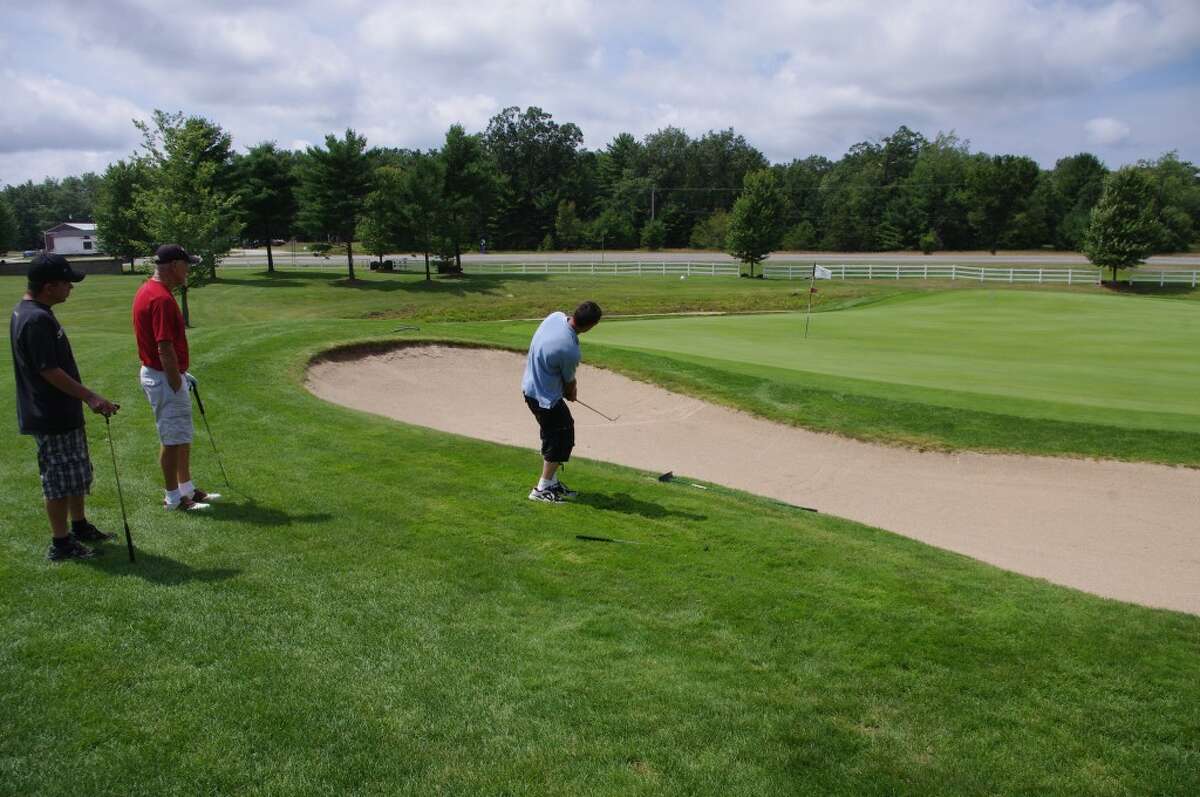 In this file photo, Ben Radlinski attempts a chip shot over the sand trap onto the green during a FiveCAP Golf for Warmth event held at Manistee National Golf & Resort.