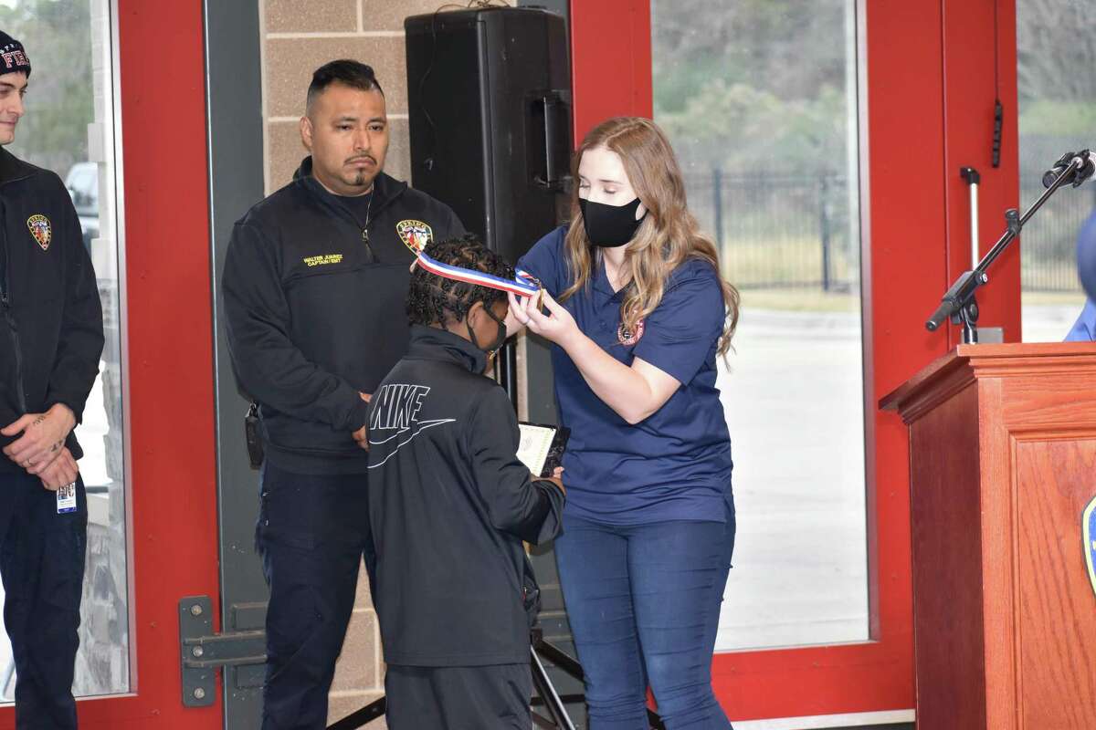 Bree Burger from the Texas Emergency Communications Center (TECC) presents Justin Clayton, Jr. with his 9-1-1 Kid Hero Award.