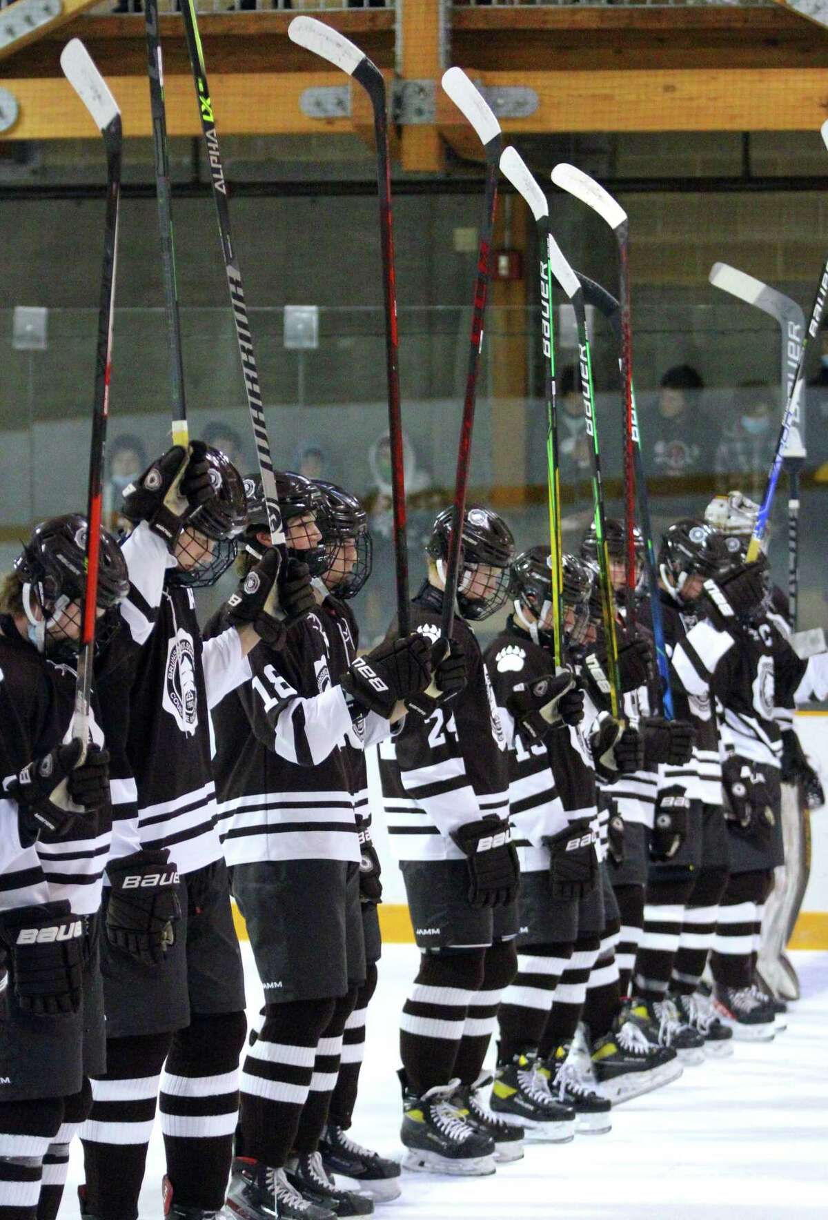 Brunswick hockey team players hold up their hockey sticks during a moment of silence before a game against Millbrook at Hartong Rink in Greenwich, Conn., on Wednesday Jan. 12, 2021. The moment of silence was held in memory of St. Luke's Teddy Balkind, who died Thursday at rink in a junior varsity game against Brunswick.