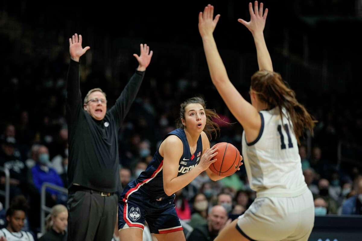 Connecticut guard Caroline Ducharme, center, looks at the basket over Butler guard Tenley Dowell (11) as Butler head coach Kurt Godlevske encourages a defensive position in the first half of an NCAA college basketball game in Indianapolis, Wednesday, Jan. 12, 2022. (AP Photo/AJ Mast)