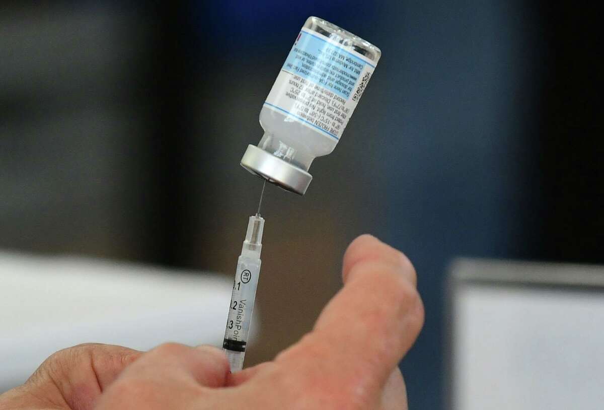 Dr. Jose Cara loads a dose into a syringe during the Darien booster clinic Tuesday, December 7, 2021 at Town Hall in Darien, Conn. The town is currently experiencing a surge in COVID cases and officials are asking everyone to stay vigilant.