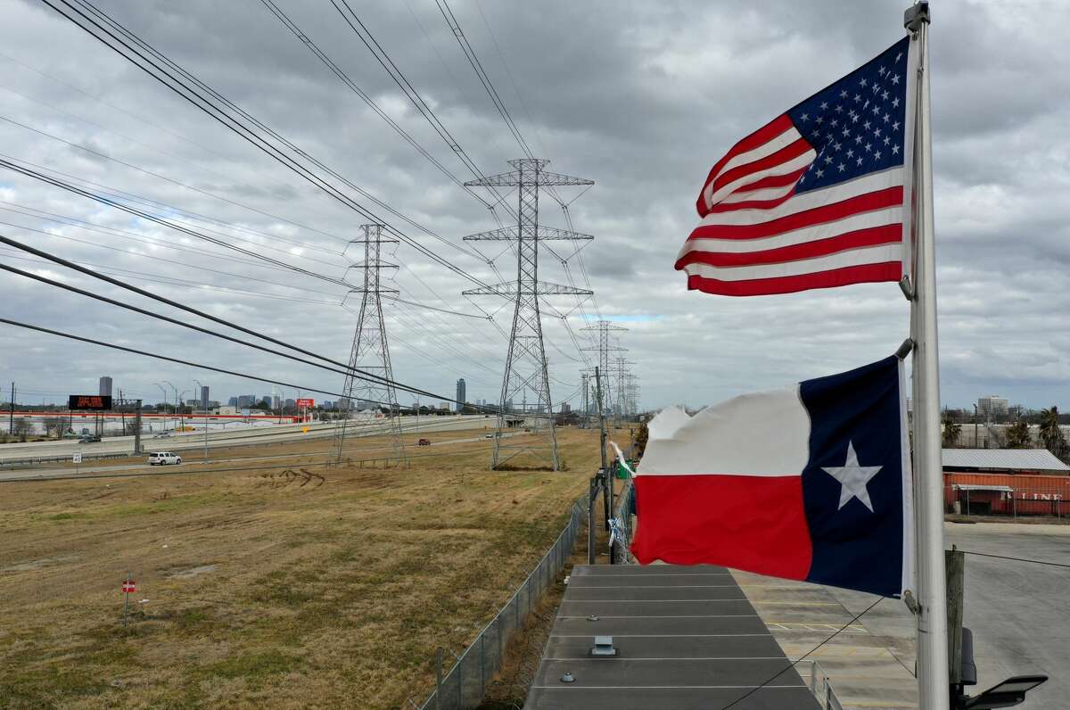 HOUSTON, TEXAS - FEBRUARY 21: The U.S. and Texas flags fly in front of high voltage transmission towers on February 21, 2021 in Houston, Texas. Millions of Texans lost power when winter storm Uri hit the state and knocked out coal, natural gas and nuclear plants that were unprepared for the freezing temperatures brought on by the storm. Wind turbines that provide an estimated 24 percent of energy to the state became inoperable when they froze. (Photo by Justin Sullivan/Getty Images)