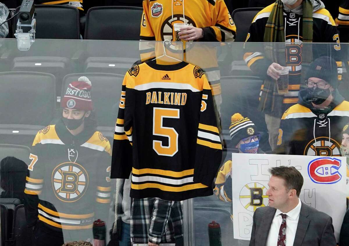A jersey for Teddy Balkind, a 16-year-old who died from an injury sustained in a Connecticut high school hockey game, hangs above the Boston Bruins bench before the start of an NHL hockey game against the Montreal Canadiens, Wednesday, Jan. 12, 2022, in Boston. (AP Photo/Mary Schwalm)