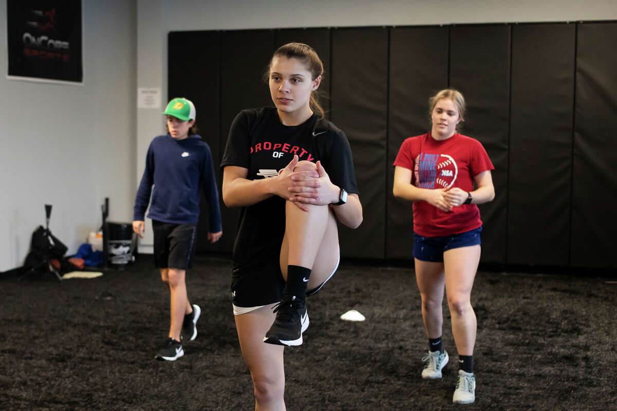 From left, Dow High freshman Brooklen Gillis, senior Taylor Huschke, and sophomore Delaney Belding warm up before a training session Wednesday, Jan. 12, 2022 at OnCore Sports in Midland.