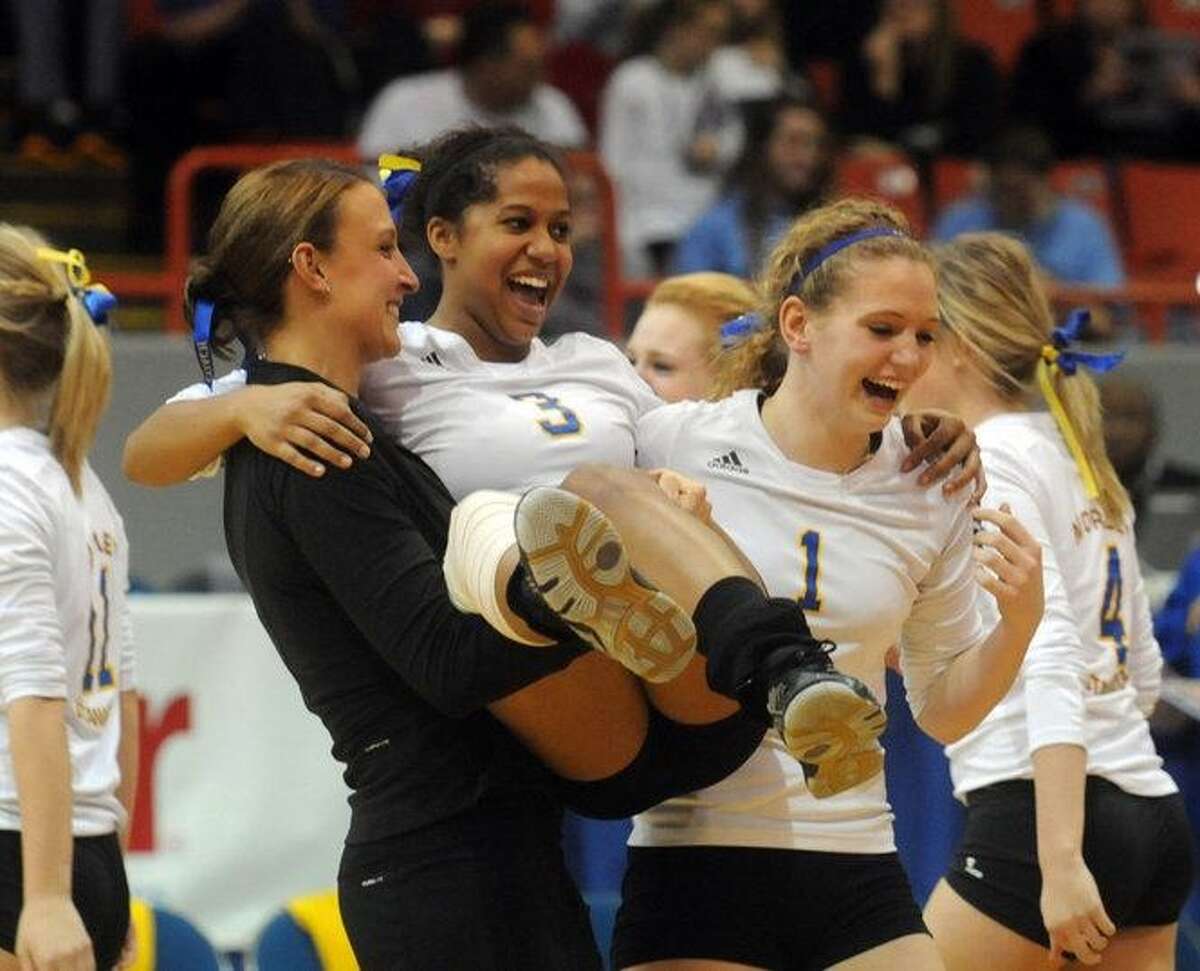 From left-to-right: Morley Stanwood volleyball coach Robin Kozuch celebrates with Brianna Wiersma and Andi Paulson after winning the 2011 state championship.