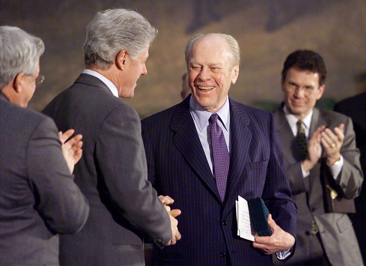 Former President Gerald Ford (2nd R) shakes hands with Bill Clinton as Speaker of the House Dennis Hastert and Senate Minority Leader Tom Daschle look on during the Congressional Medal of Honor ceremony in the Rotunda of the Capitol in 1999. Ford and his wife, Betty, were awarded the medal for their public service.