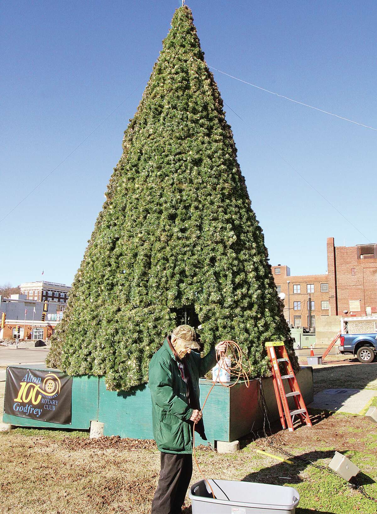 John Badman|The Telegraph Members of the Alton-Godfrey Rotary Club did some pre-takedown work Thursday afternoon at the Christmas tree they erect each year in Lincoln-Douglas Square. The men were removing and storing away all of the extension cords used to power the lights on the tree. Actual work to take down the tree, which is more than a quarter of a century old, will be done on a future weekend -- but not this one due to the forecast for snow.