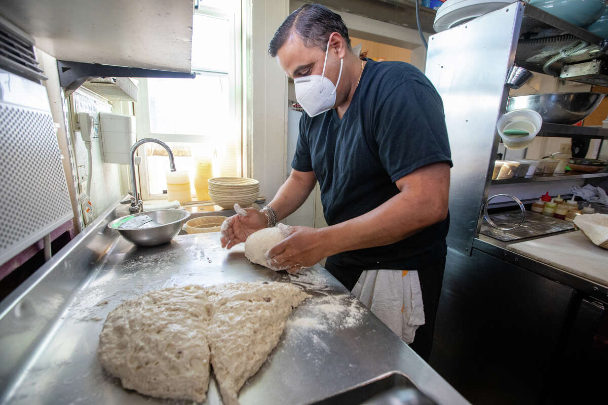 Owner and chef Sachin Chopra works on shaping some sourdough bread in the kitchen of All Spice restaurant in San Mateo, Calif., on Jan. 11, 2022.