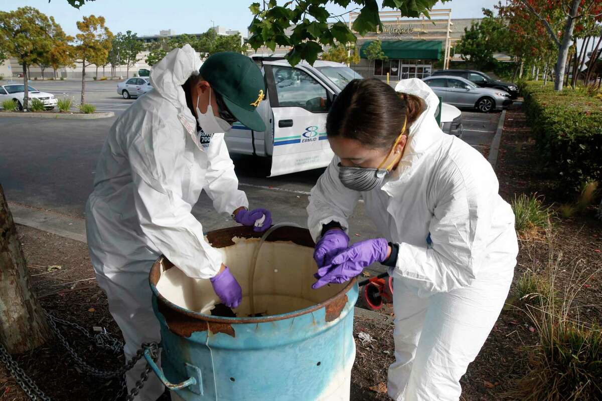 Zach Wu and Gabriela Esparza, wastewater control inspectors with the East Bay Municipal Utility District, retrieve collection equipment and samples in Oakland in July 2020. The samples are sent to labs to analyze for any detection of the coronavirus in the sewage system.