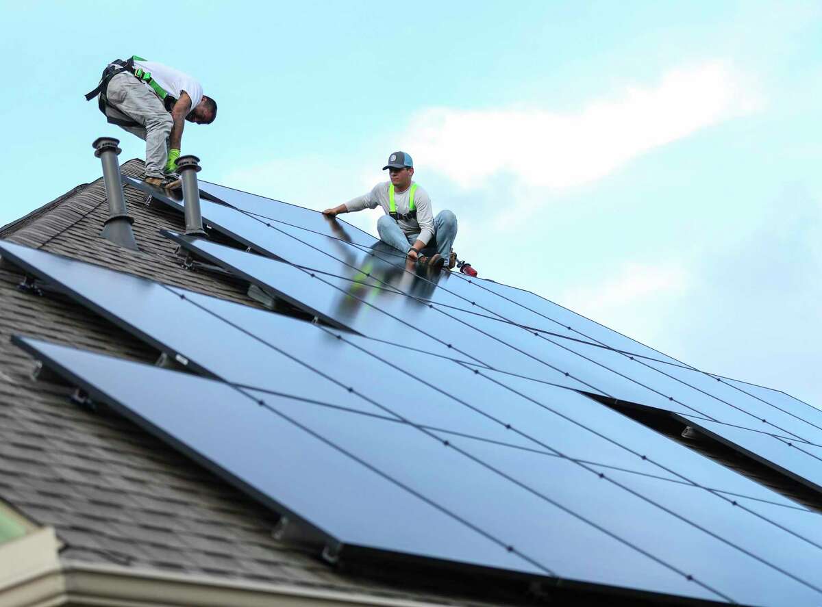 Daniel Molina and Dion Worrel with Texas Solar Outfitters, install solar panels on a home, Friday, Dec. 17, 2021 in Cypress.