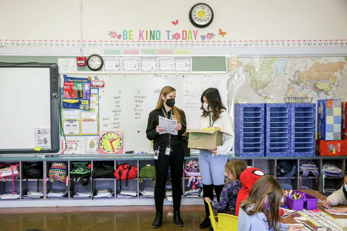 Principal Lauren Ashton explains distribution of at-home COVID-19 testing kits to first-grade teacher Nadia Lau in her classroom at West Portal Elementary in San Francisco.