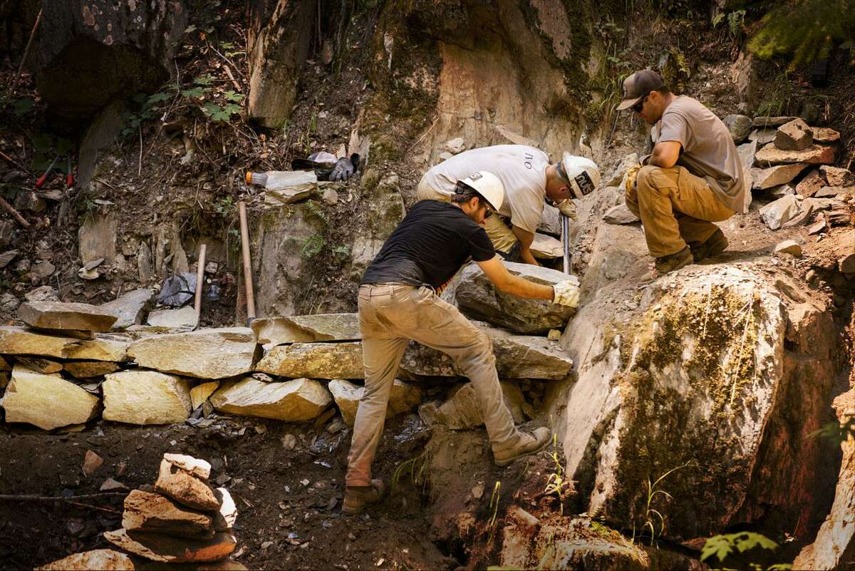 The trail crew of the Sierra Buttes Trail Stewardship builds a trail foundation in steep terrain.