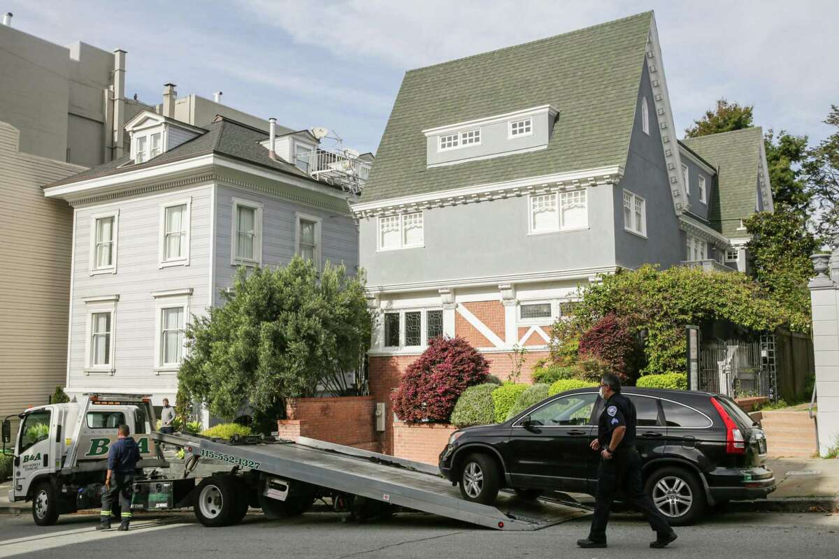 San Francisco parking control officer Nestor Guevarra walks toward a truck towing a car parked illegally in front of a home.
