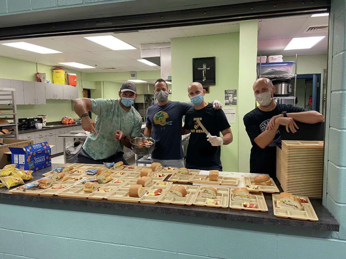 From left, Former NFL player Jared Veldheer, cafeteria volunteers Brian Reilly and Joe Annoreno, and kitchen assistant Brady Hunt plate up Italian subs. CREDIT: Photo courtesy of Katie Tietema