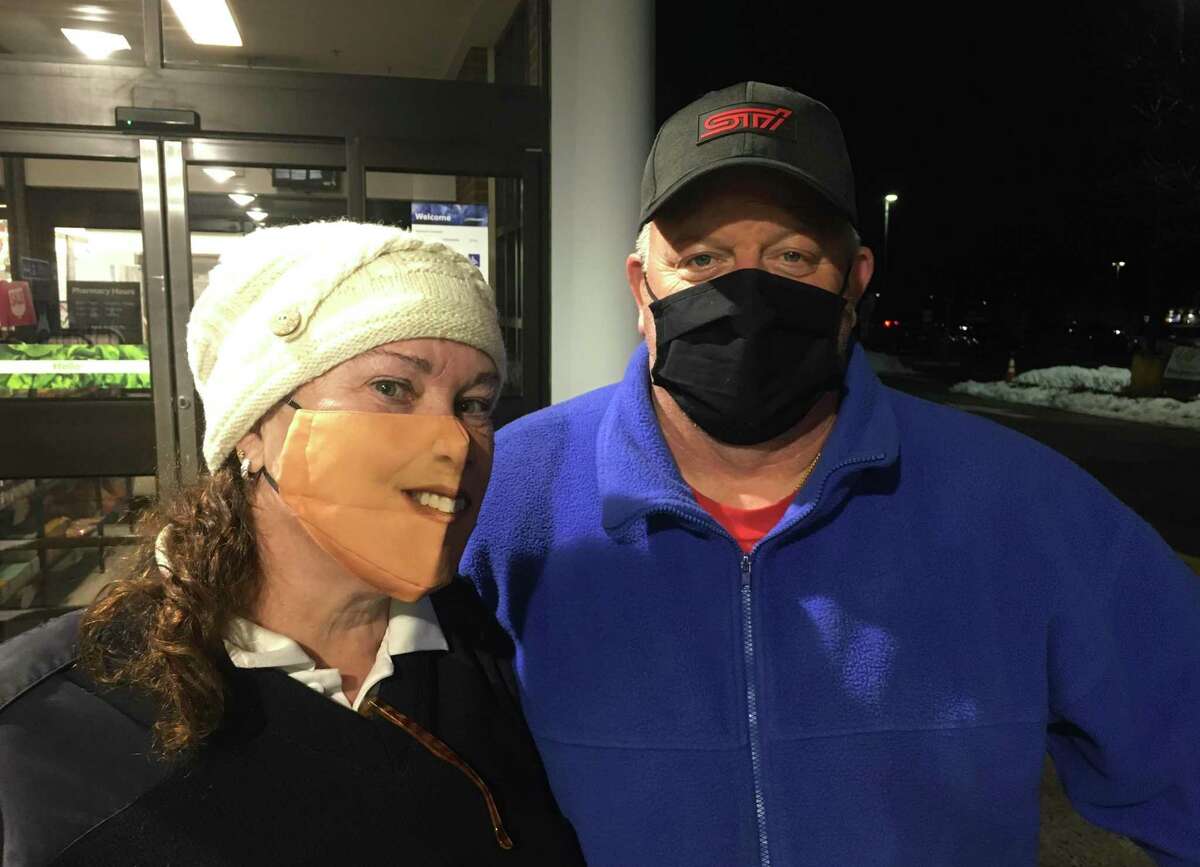 A mask-wearer named Janice, left, has drawn a lot of attention from a face-covering she wore at a Norwalk supermarket Thursday, where she is shown with her friend named Scott. The mask is based on a photograph of her face. People respond with humor but it started with a serious purpose. “I honestly did it because my mother had dementia,” she said, and did not easily recognize her with a mask on. Janice and Scott asked that their names not be used.