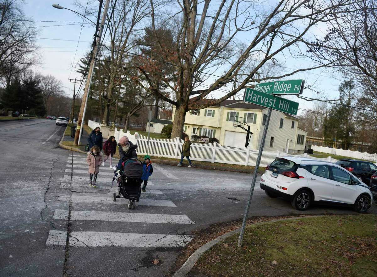 Pedestrians cross the intersection of Pepper Ridge Road and Harvest Hill Lane after dismissal at Newfield Elementary School in Stamford, Conn. Thursday, Jan. 6, 2022. The Board of Representatives recently approved a resolution to give the intersection the honorary name of “Roosevelt Mitchell Crossing” in honor of the longtme crossing guard who died last September.