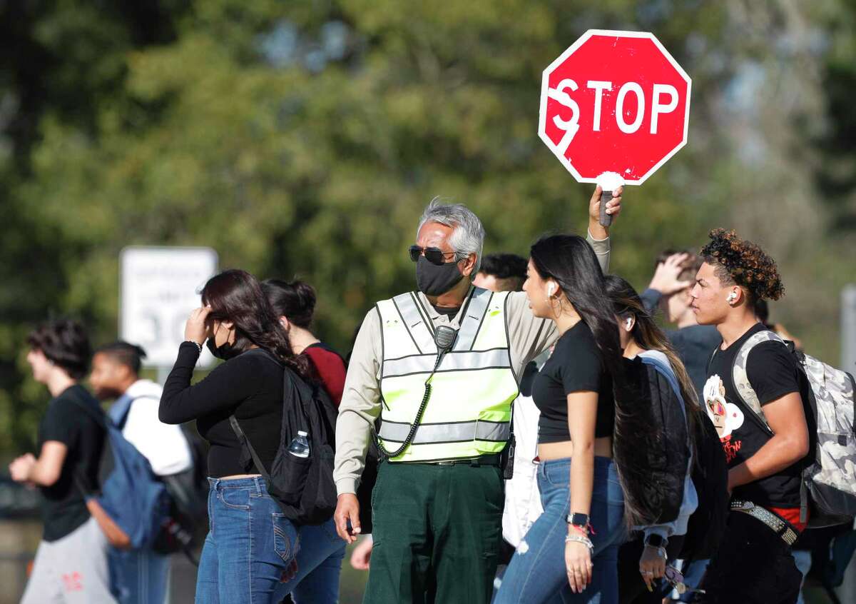 A crossing guard wears a face mask as he guides students across Oak Ridge School road after Oak Ridge High School let out for the day, Wednesday, Jan. 5, 2022. Conroe ISD students, faculty and staff returned to school from the winter break as Montgomery County reported an increase of more than 5,000 new COVID-19 cases since last Tuesday.