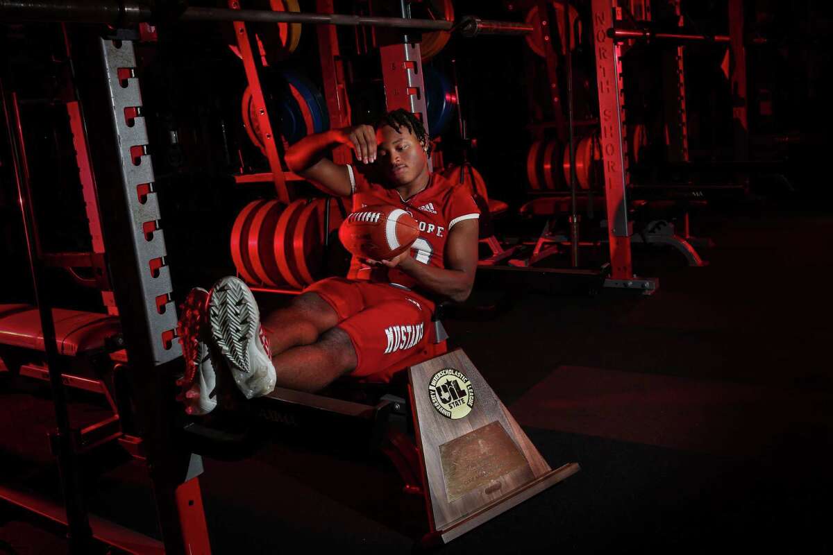 North Shore Mustangs middle linebacker Kent Battle (10) poses for a portrait with the teams 6A State Championship trophy Wednesday, Jan. 12, 2022, in the team’s weight room at North Shore Senior High School in Houston.