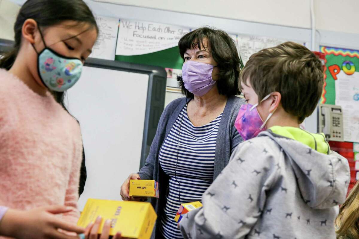 Second-grade teacher Mary Peralta distributes at-home COVID-19 testing kits to her students at West Portal Elementary in San Francisco. The current coronavirus surge appears to have peaked across much of the Bay Area though not everywhere.