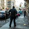 A San Francisco police officer patrols near a row of tents along Hyde Street in the Tenderloin. More outreach is being done in the troubled neighborhood.