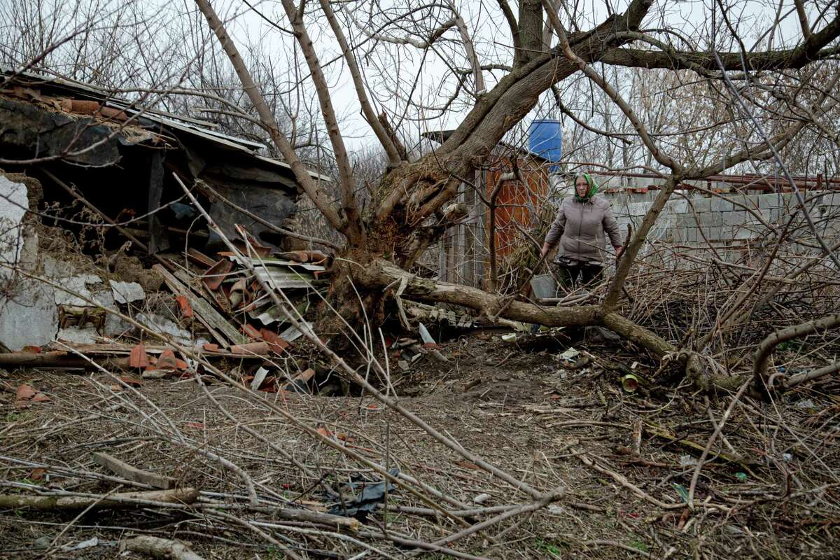Liudmyla Kulik stands near her damaged hen house and a fallen tree on Dec. 14. The damage was caused by shelling in October in Hranitne, Ukraine.