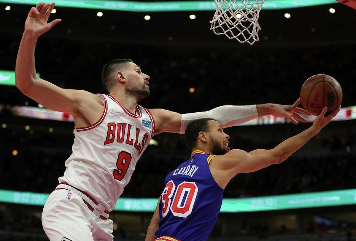 Nikola Vucevic of the Chicago Bulls defends a shot by Stephen Curry of the Golden State Warriors during the second half Friday night’s game at United Center.
