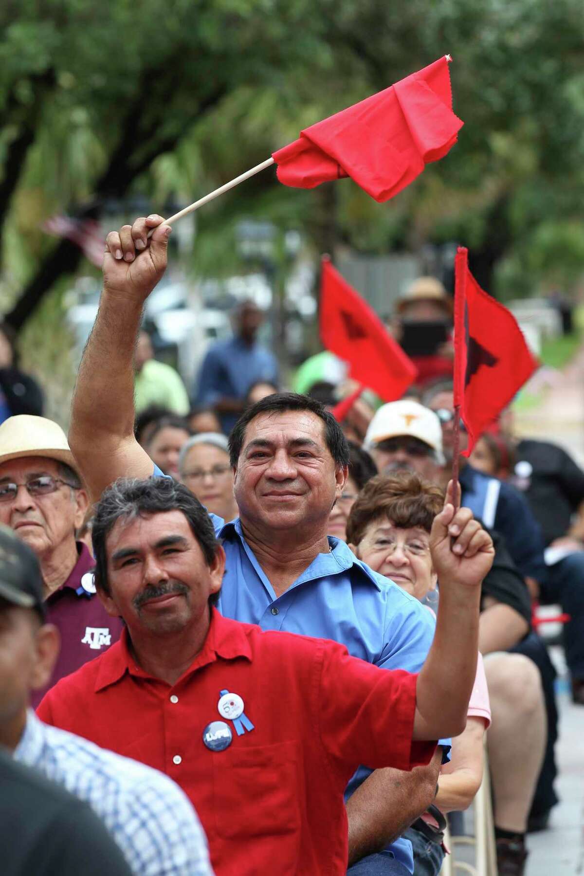 Jose Aldape, 51, foreground in red, of Mercedes, Texas and Adan Arredondo, 54, of Rio Grande City, in blue, wave their flags in support as people gather to commemorate the 50th anniversary of the 1966 Melon Strike in Starr County during a ceremony in Rio Grande City, Wednesday, June 1, 2016. The strike was started in an effort to raise the minimum wage of farmworkers from 25 cents an hour to $1.25.