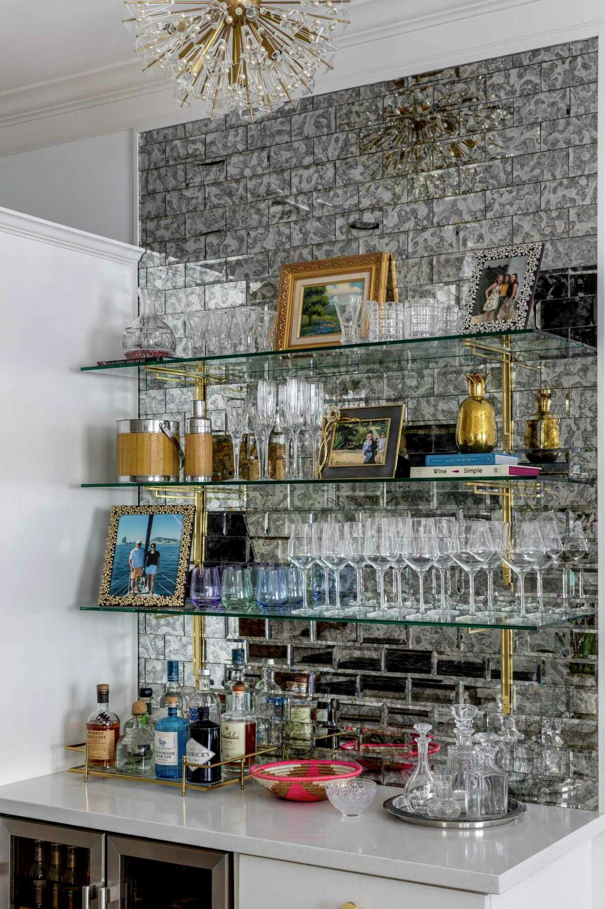What used to be a small desk was reinvented as a bar with glass shelves on an antique mirror tiled wall.