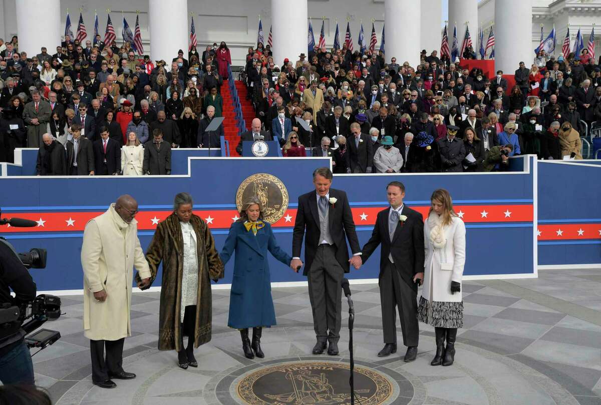 From left: Terence Sears, Lt. Gov. Winsome Sears, Suzanne Youngkin, Gov. Glenn Youngkin, Attorney General Jason Miyares and Page Atkinson Miyares hold hands as the new governor leads a prayer.