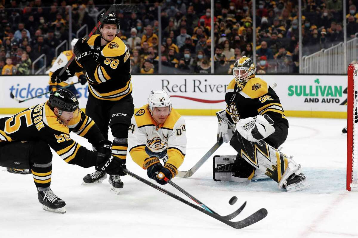 Nashville Predators' Mikael Granlund dives for a loose puck in front of Boston Bruins goaltender Linus Ullmark with defenseman Tyler Lewington, left, during the second period of an NHL hockey game Saturday, Jan. 15, 2022, in Boston. (AP Photo/Winslow Townson)