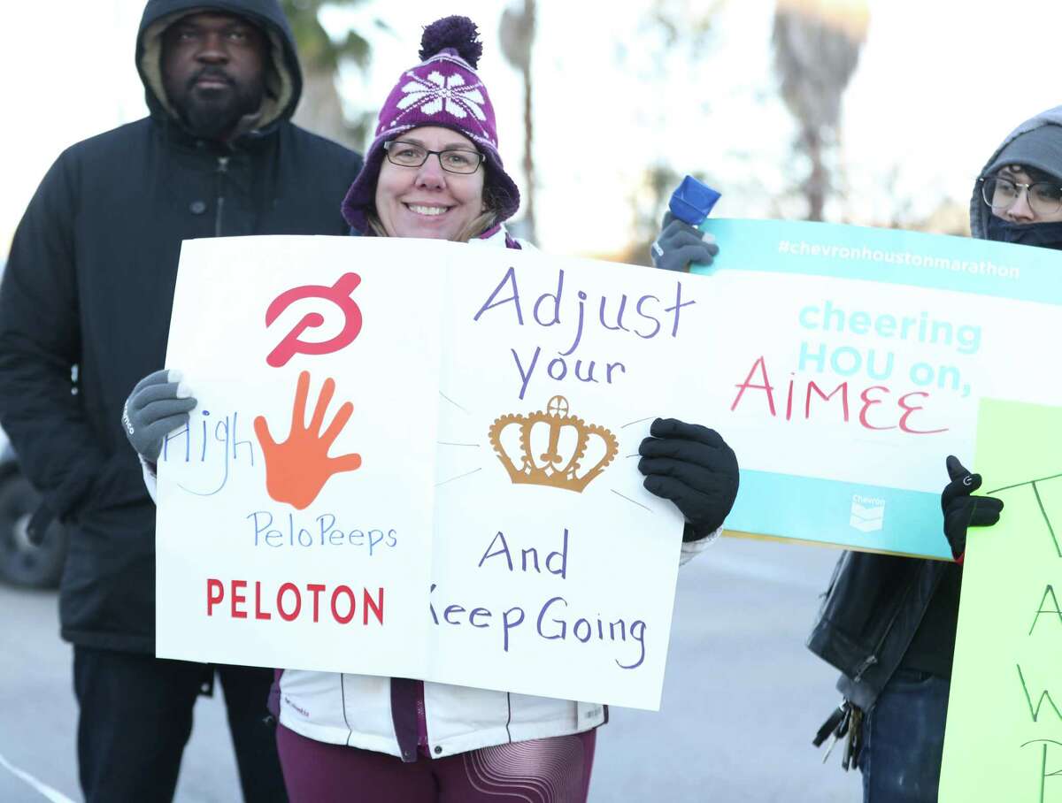 People cheer runners with signs during the Chevron Houston Marathon along Washington Avenue near Waugh, Sunday, Jan. 16, 2022 in Houston.