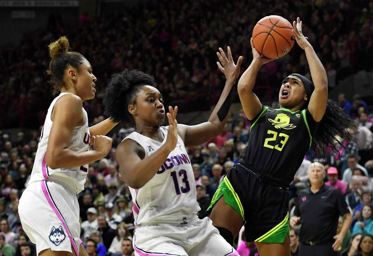 Oregon’s Minyon Moore, right, shoots as UConn’s Olivia Nelson-Ododa, left, and Christyn Williams defend on Feb. 3, 2020, in Storrs. UConn and Oregon meet again Monday in Eugene, Ore.