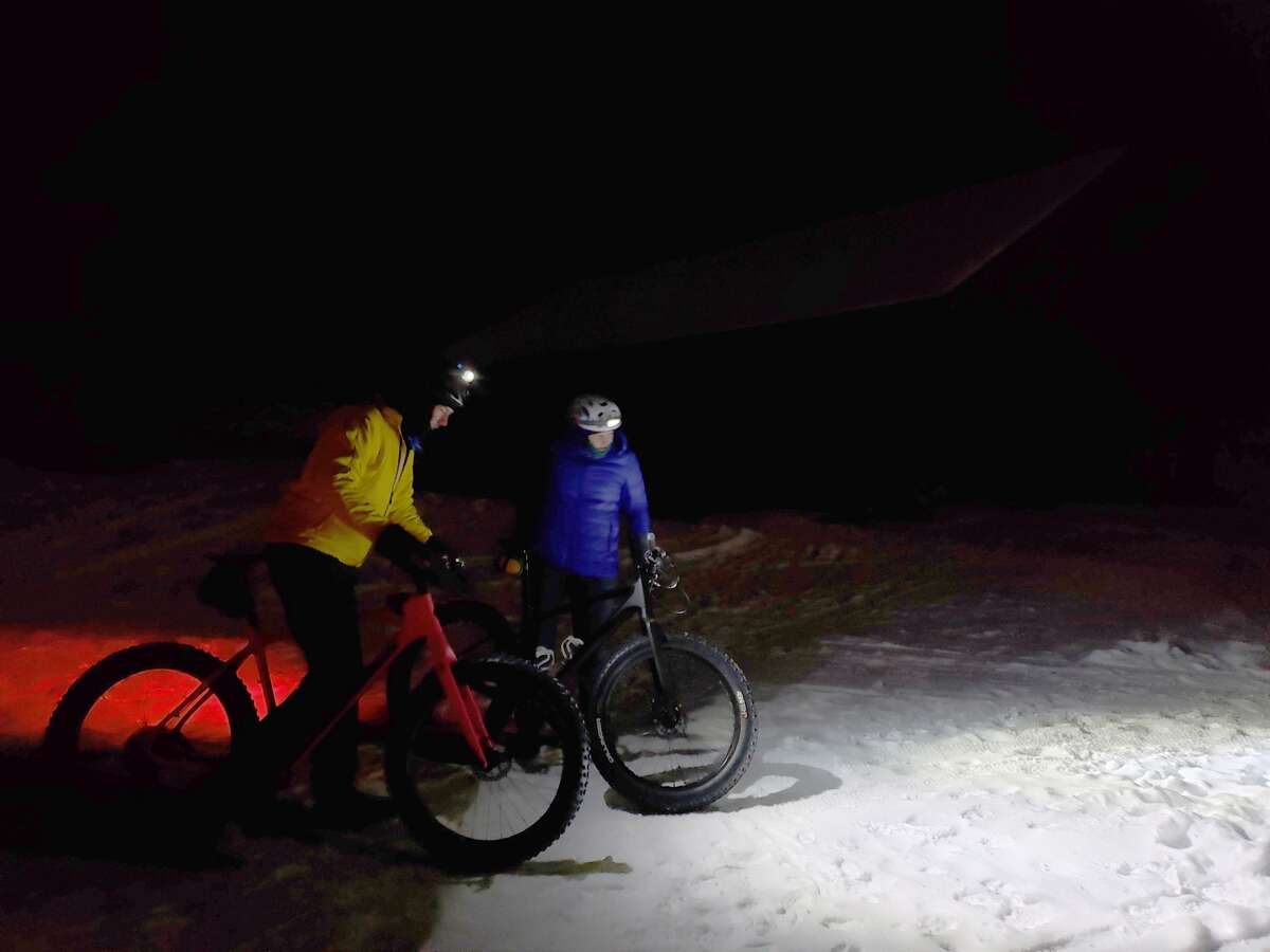 Wayne Stroope and Sue Stroope take off for a fat tire bike run through Big M's trail system on Saturday during a moonlight winter sporting gathering.