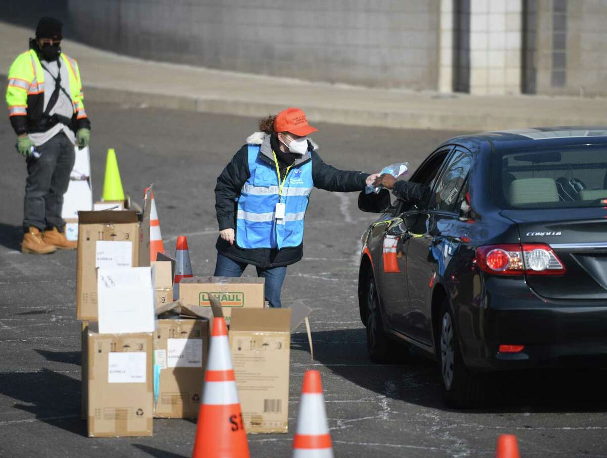 Suzanne Scott hands out masks at AITE High School in Stamford, Conn. Sunday, Jan. 16, 2022. 2,500 five-packs of N95 masks and 2,500 five-packs of surgical masks were distributed to Stamford residents in a drive-thru and walk-up fashion on Sunday.