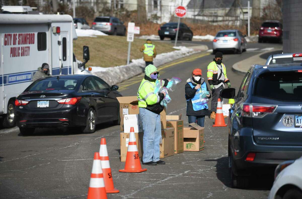 Masks are distributed at AITE High School in Stamford, Conn. Sunday, Jan. 16, 2022. 2,500 five-packs of N95 masks and 2,500 five-packs of surgical masks were distributed to Stamford residents in a drive-thru and walk-up fashion on Sunday.