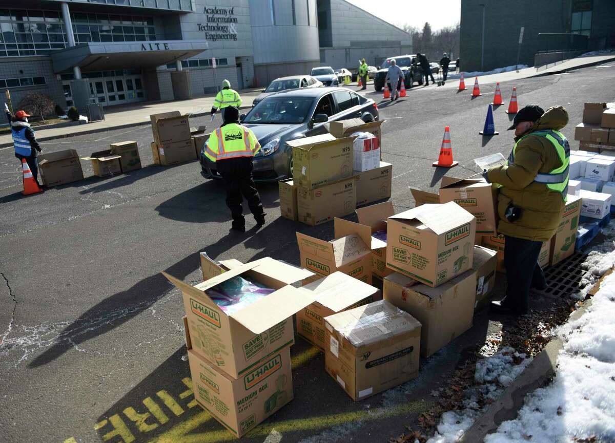 Masks are distributed at AITE High School in Stamford, Conn. Sunday, Jan. 16, 2022. 2,500 five-packs of N95 masks and 2,500 five-packs of surgical masks were distributed to Stamford residents in a drive-thru and walk-up fashion on Sunday.