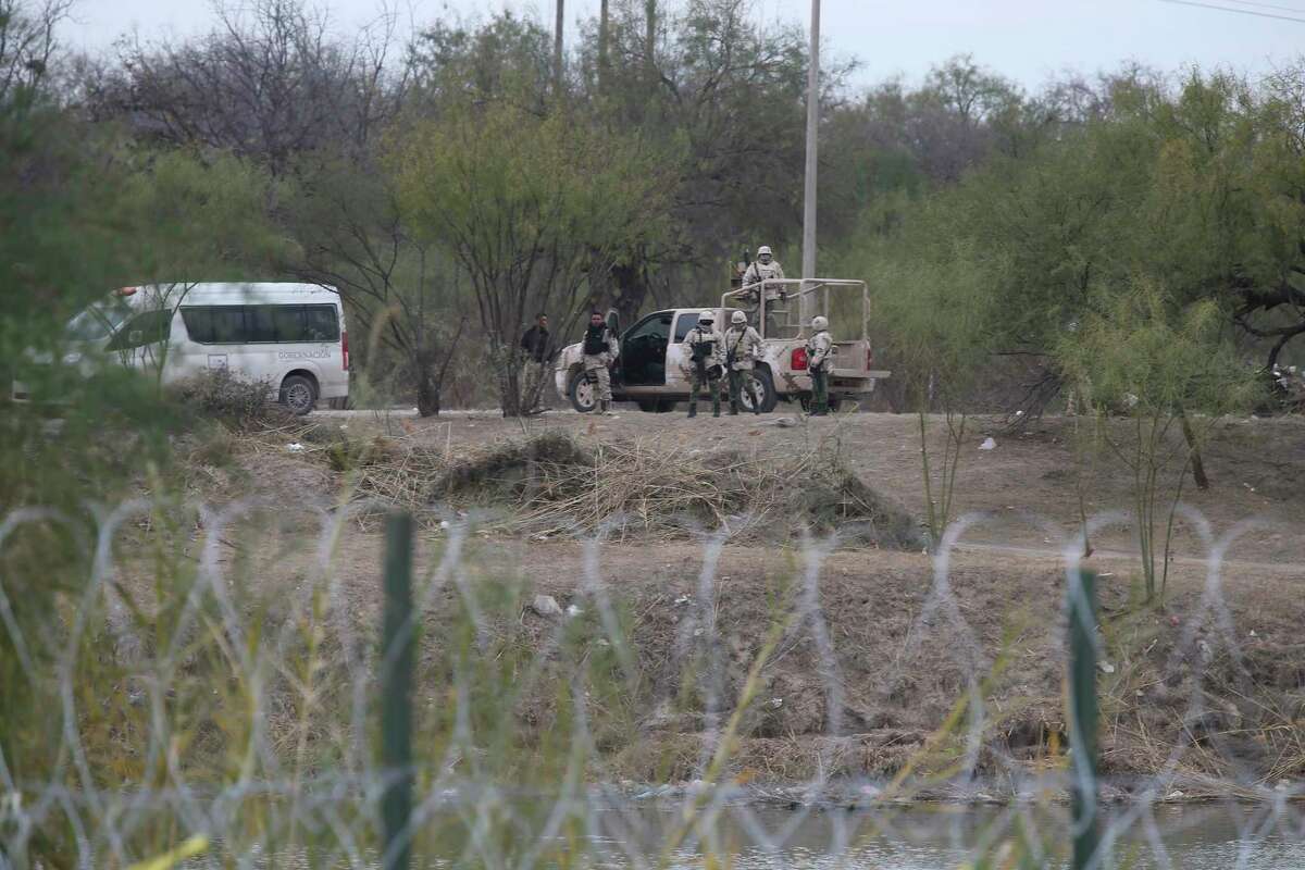 Mexican soldiers and officials are seen on the banks of the Rio Grande across from Eagle Pass Wednesday. A group of migrants were attempting to cross into the U.S. nearby and the officials turned them away and back into Mexico.