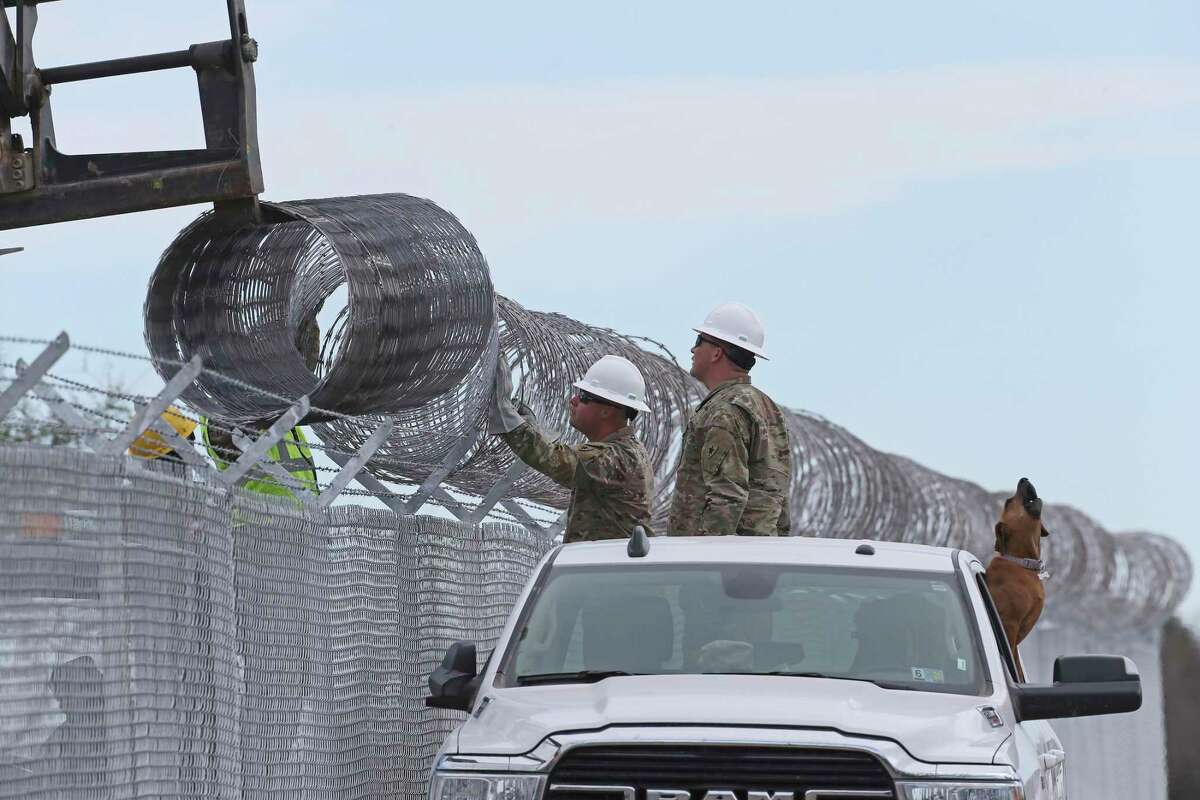 Texas National Guard soldiers work to install fencing along Vega Verde Road in Del Rio on Monday. The road hugs the Rio Grande.