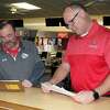 Chippewa Hills bowling coaches Casey Russell (left), for the boys, and Chris Stirn, for the girls, review their scores at Remus Lanes after Saturday's CSAA Gold Division matches.