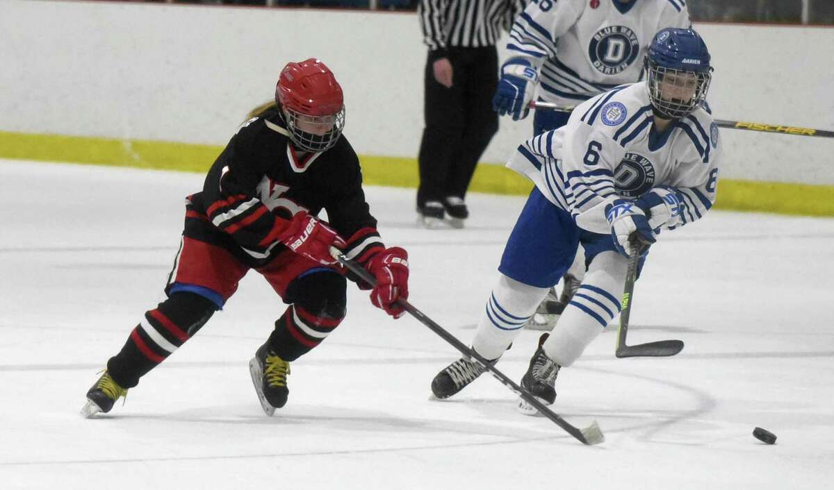 New Canaan's Maddie Kloud (7) and Darien's Skylar Ravosa (6) race to the puck during a girls ice hockey game at the Darien Ice House on Monday, Jan. 10, 2022