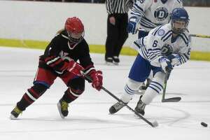 New Canaan's Maddie Kloud (7) and Darien's Skylar Ravosa (6) race to the puck during a girls ice hockey game at the Darien Ice House on Monday, Jan. 10, 2022