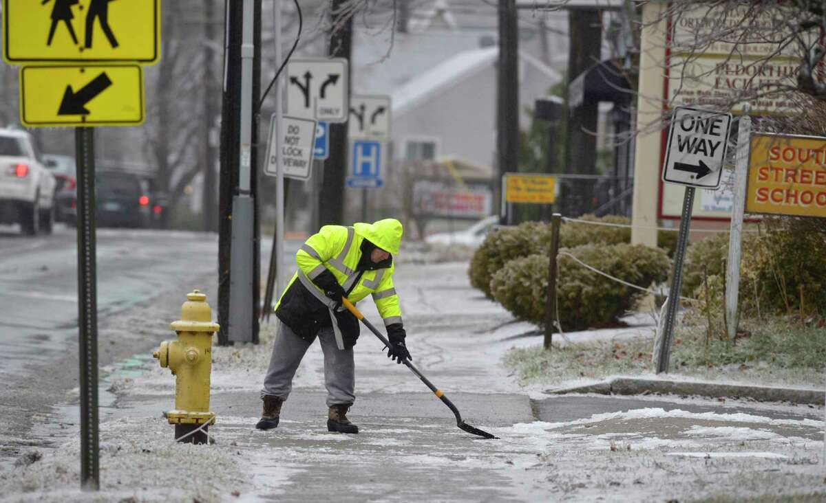 William Schuman, of Danbury, the head custodian of South Street School, scrapes ice from the sidewalk as snow and freezing rain spreads across the area on Tuesday, December 17, 2019, in Danbury, Conn. Schuman had been removing the ice all morning.
