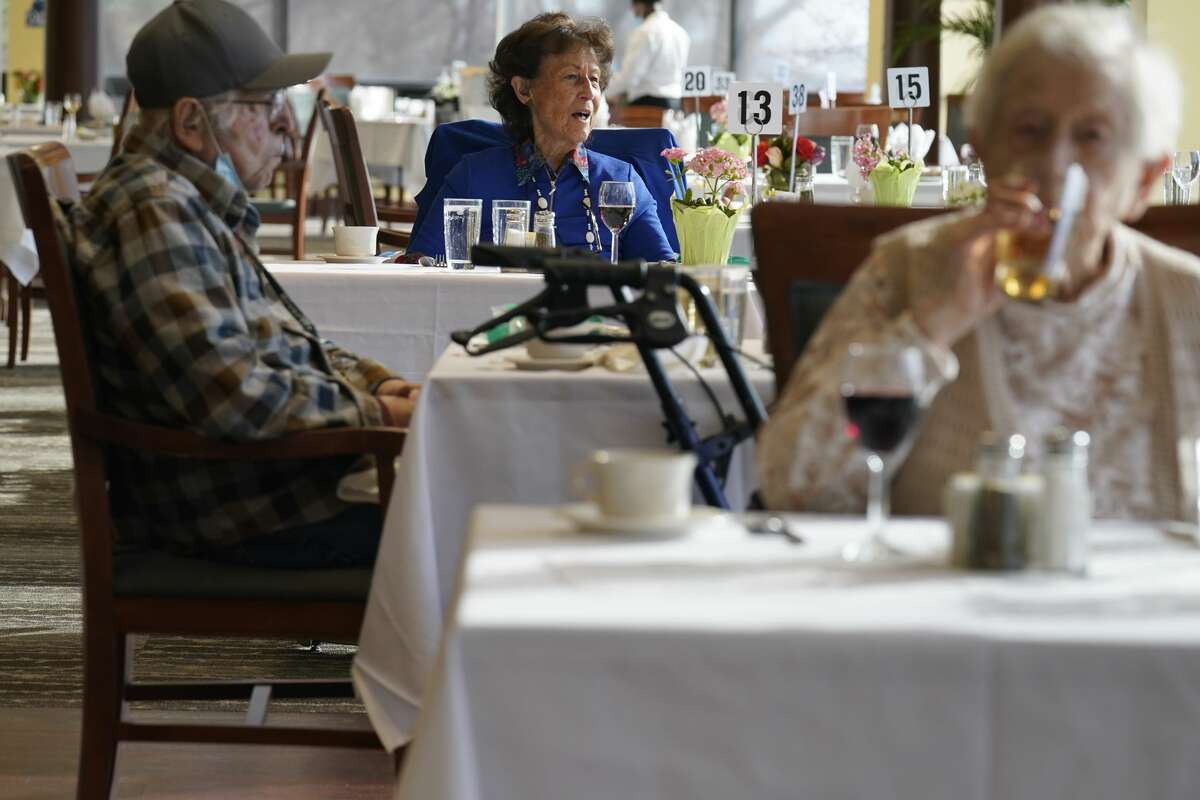 Residents dine together, but socially distant, in the dining hall of an independent senior housing facility. COVID-19 infections are soaring again at U.S. nursing homes because of the Omicron wave, and deaths are climbing too. That's leading to new restrictions on family visits and a renewed push to get more residents and staff members vaccinated and boosted.