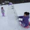 Emily Montimurro, 4, of Colonie, left, patches up a snowman with her sister Abigail, 7, at Saint Gregory’s School after a snow storm on Monday, Jan. 17, 2022 in Loudonville, N.Y.